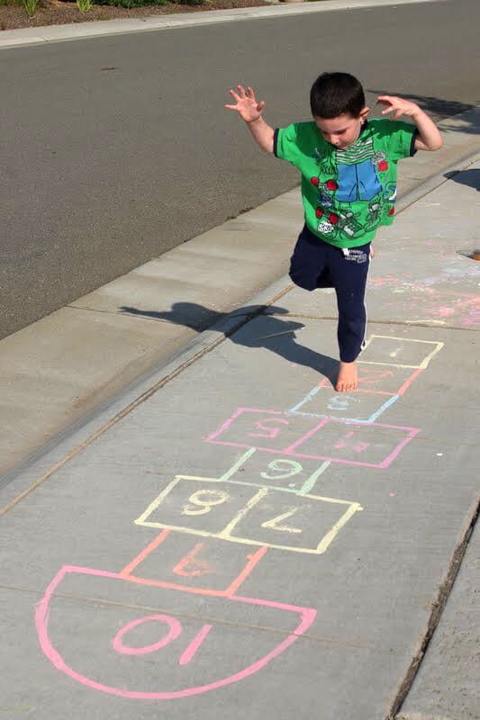 kids playing hopscotch on painted sidewalk