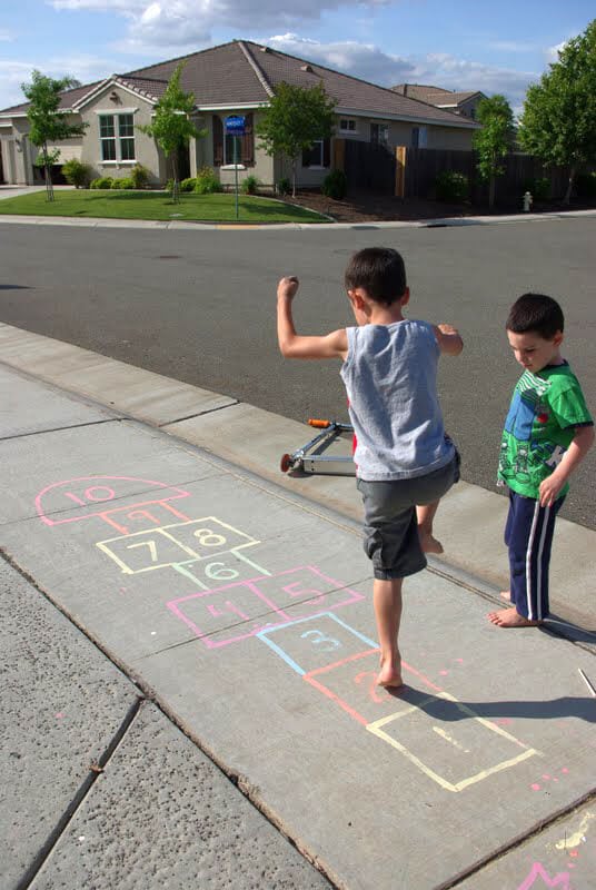 children playing hopscotch on sidewalk 