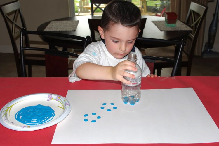 child making art using bottom of soda bottle