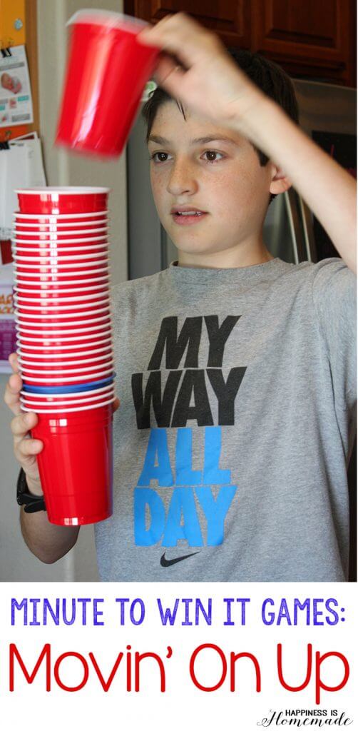 a young boy holding a stack of red cups for \'Movin On Up\' Minute-to-Win-It party games