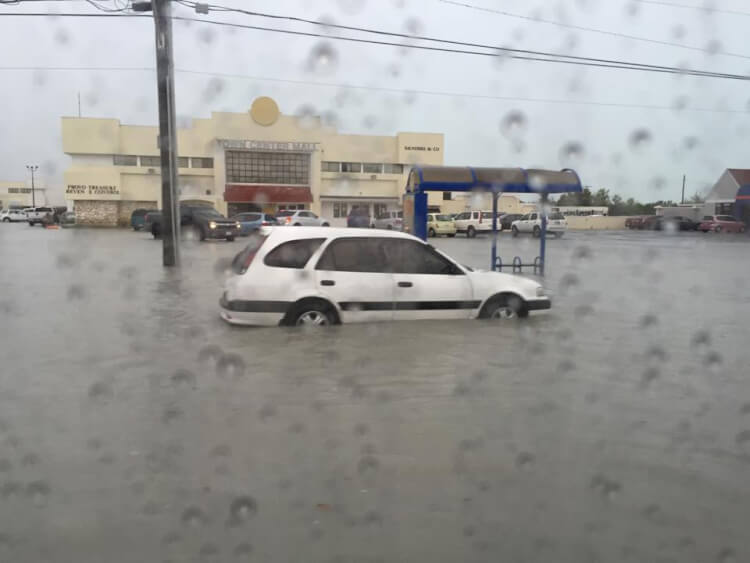 white car in rising flooded street waters 