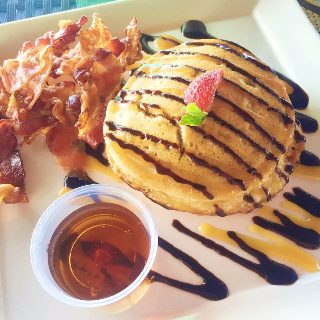 delicious pancake and bacon breakfast served on platter with syrup 