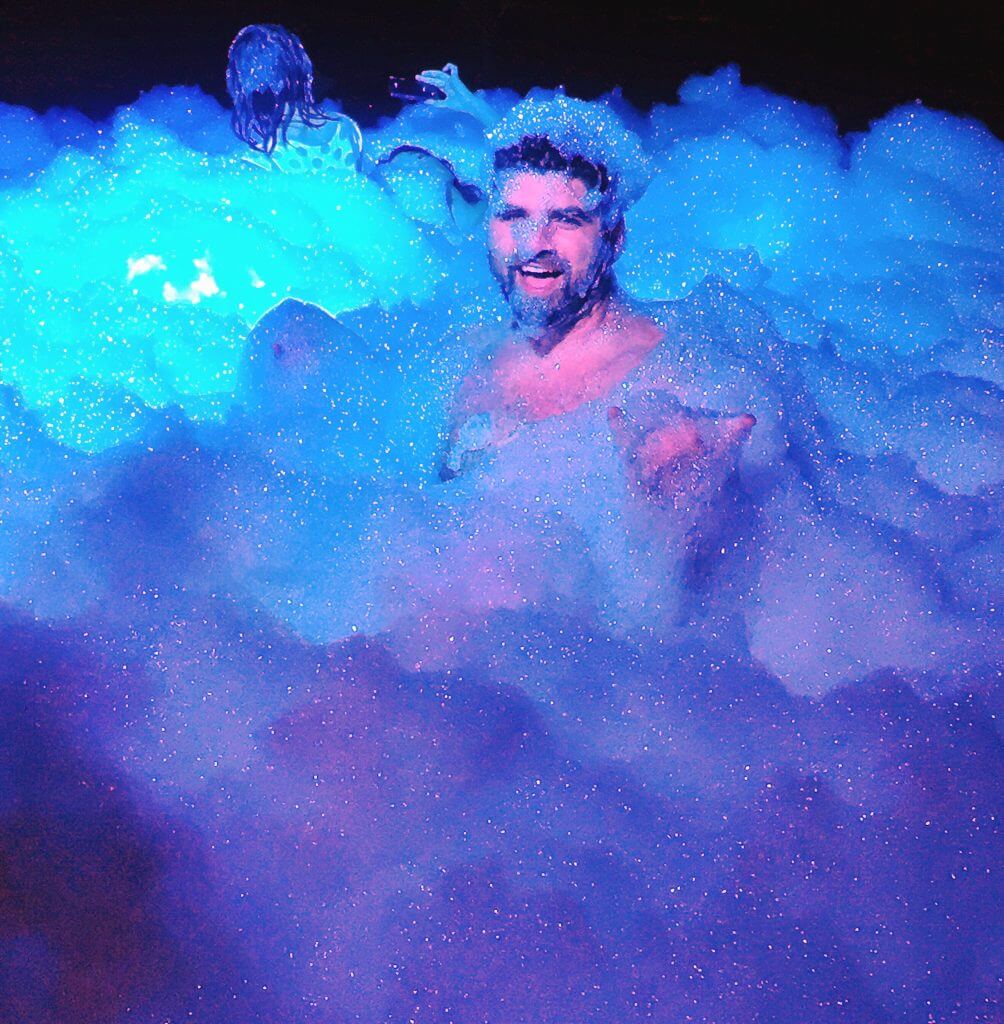 man smiling playing in a bubble foam pit 