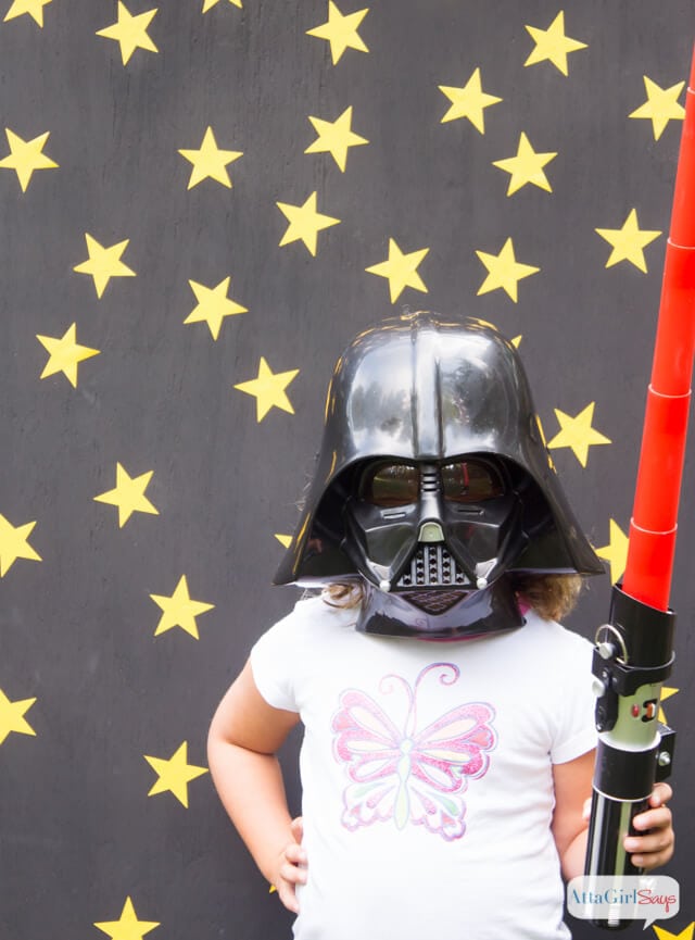 girl wearing darth vader helmet and holding lightsaber