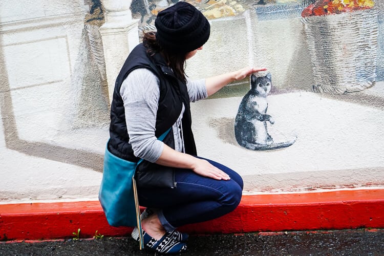 woman petting fake cat statue 
