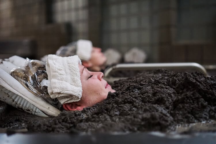 girls laying in spa mud with towels on heads