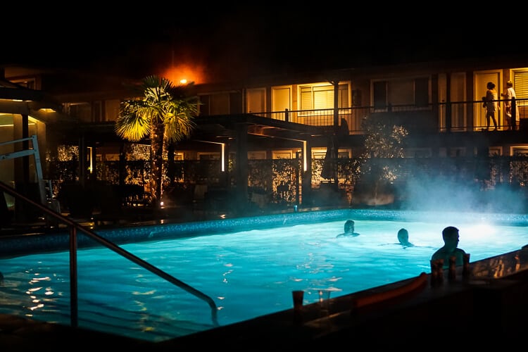 lighted hotel pool at night time with people swimming