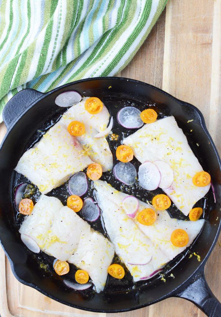 veggies added to cooking skillet of haddock