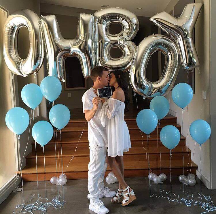 couple kissing at gender reveal party with OH BOY balloons in background