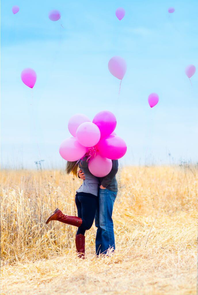 two people hugging holding pink balloon bouquet