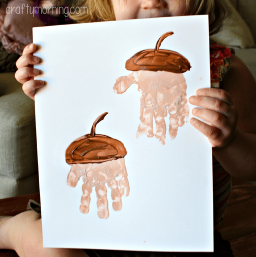 handprint made into acorn kids craft being held by child