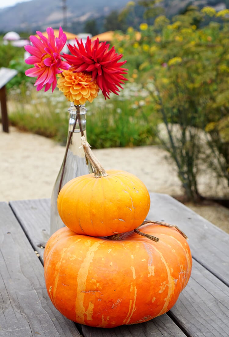 pumpkins stacked on table next to vase of flowers