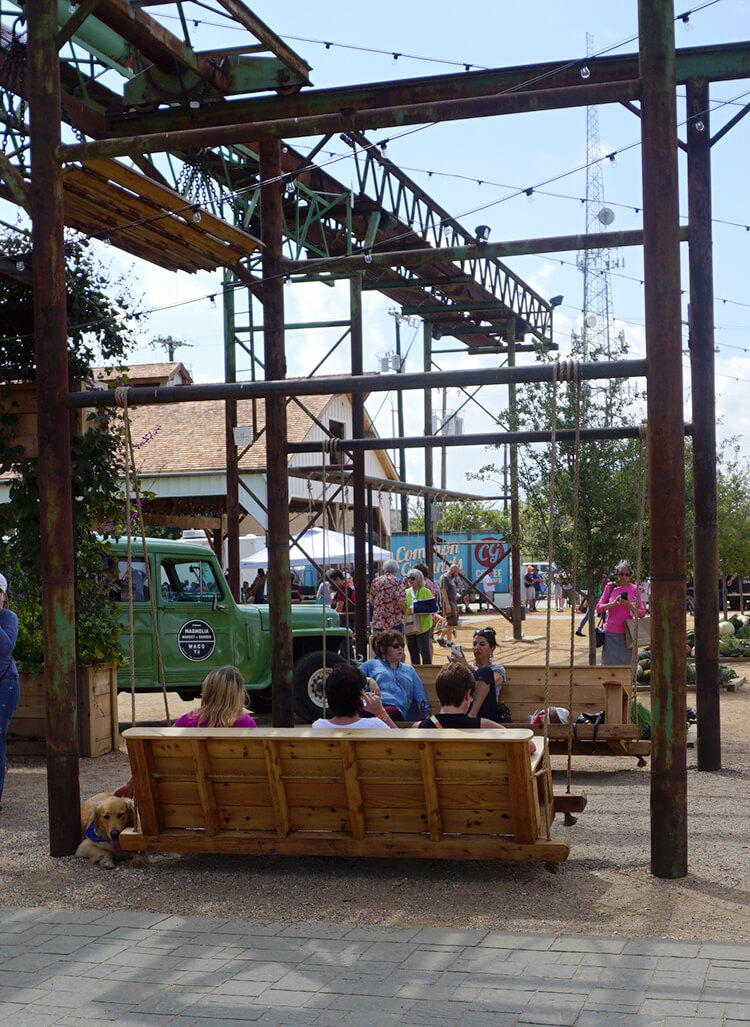 people lounging on oversized porch swings at magnolia market