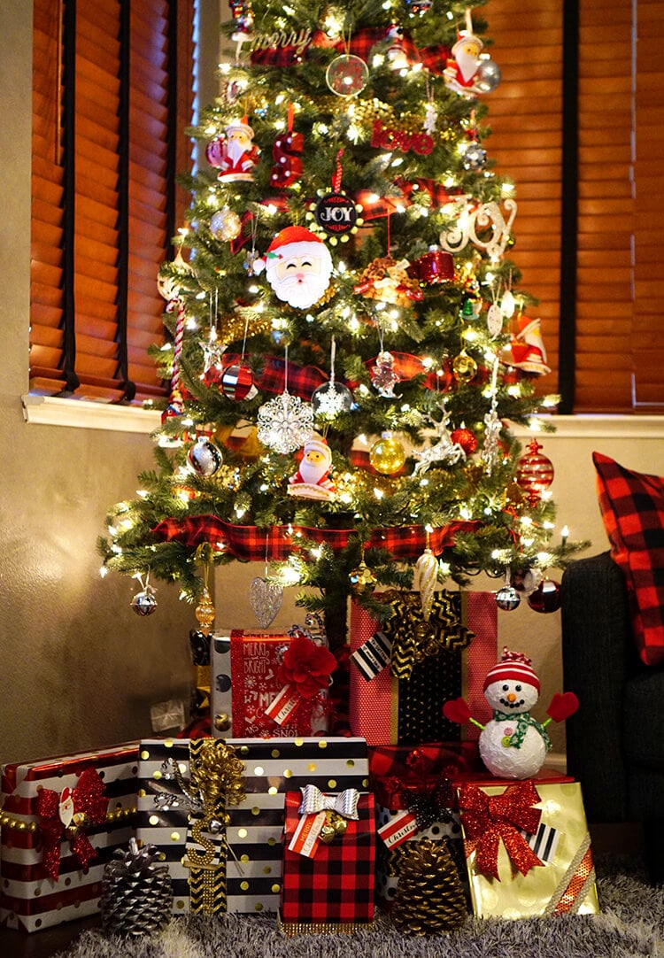 Red, black, white, and gold/silver presents underneath a Christmas tree with white lights and red/black buffalo plaid ribbon