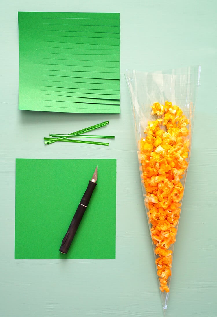 popcorn filled inside of treat bag next to sheets of green paper 