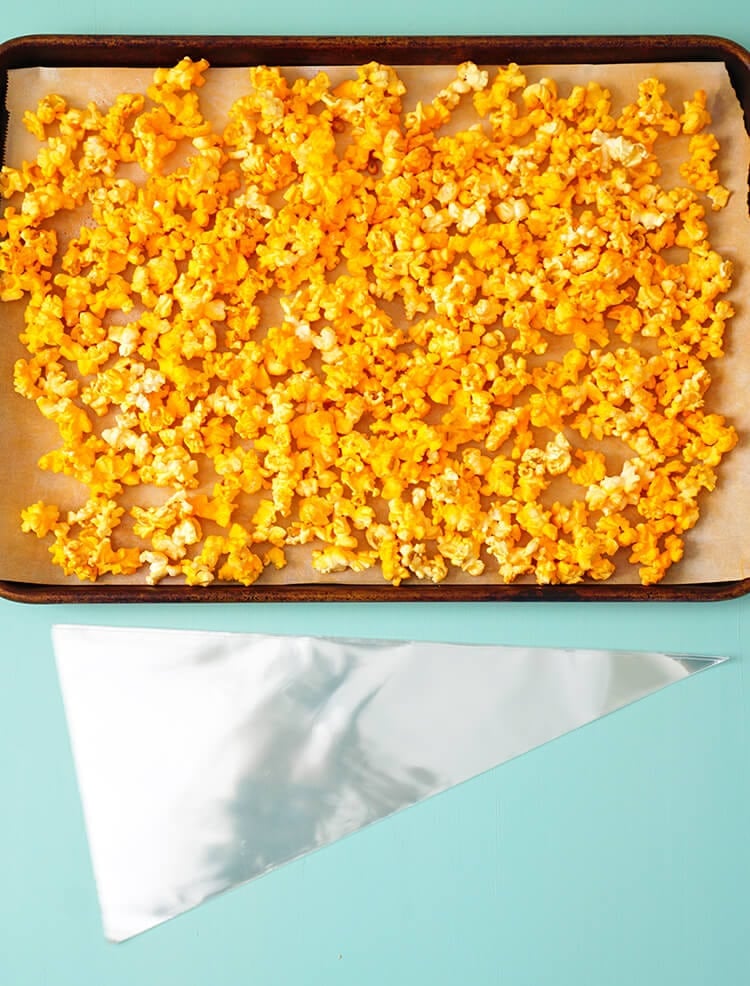 orange popcorn on baking sheet with clear plastic treat bags