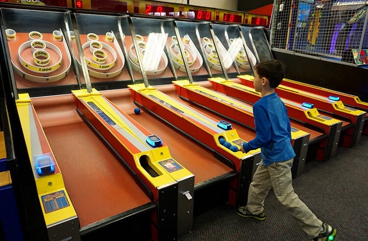 child playing skeeball game 