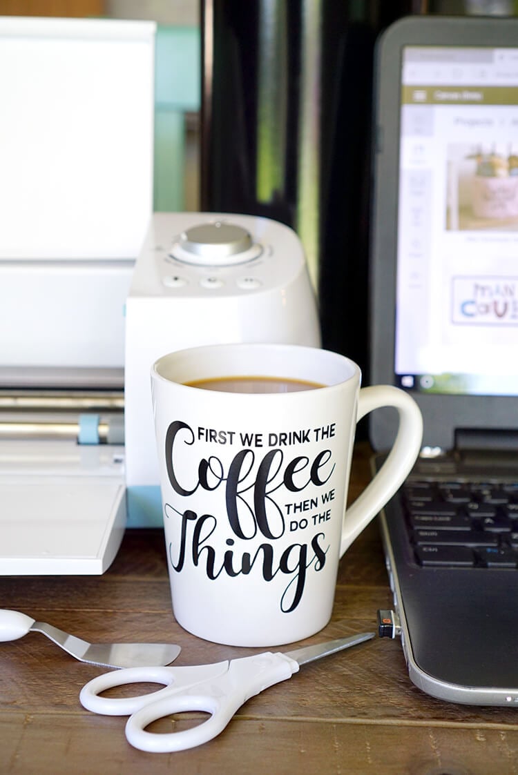 coffee mug and laptop next to cricut machine