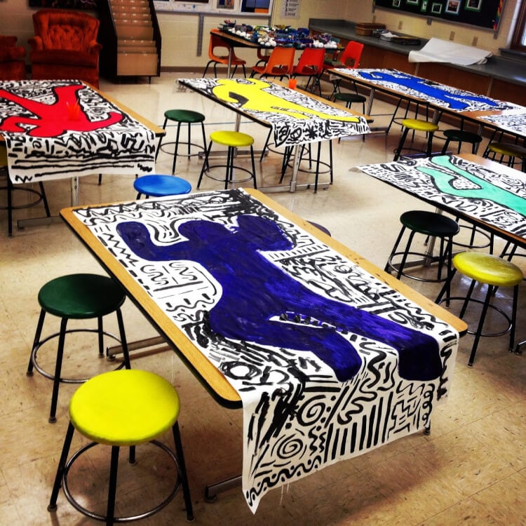 paper laid on school tables colored and depicting life size bodies colored in with doodled background