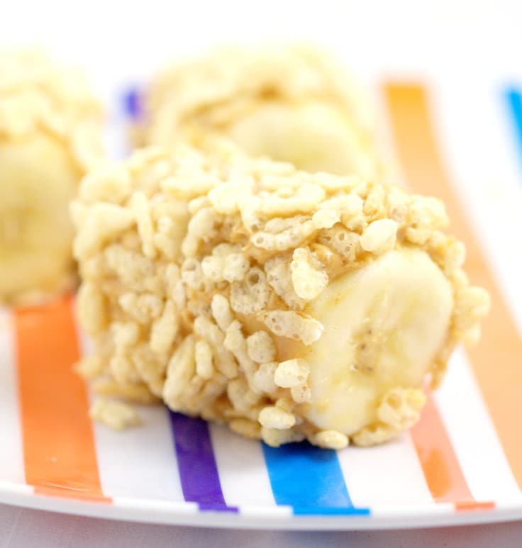 Half of a banana covered with rice cereal on a striped plate