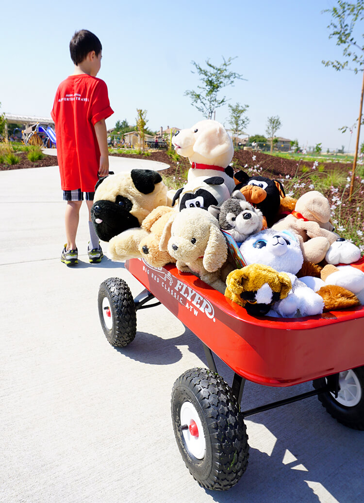 radio flyer wagon filled with stuffed animals pulled by boy