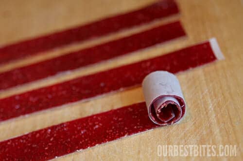 Four red fruitroll ups on a wood table