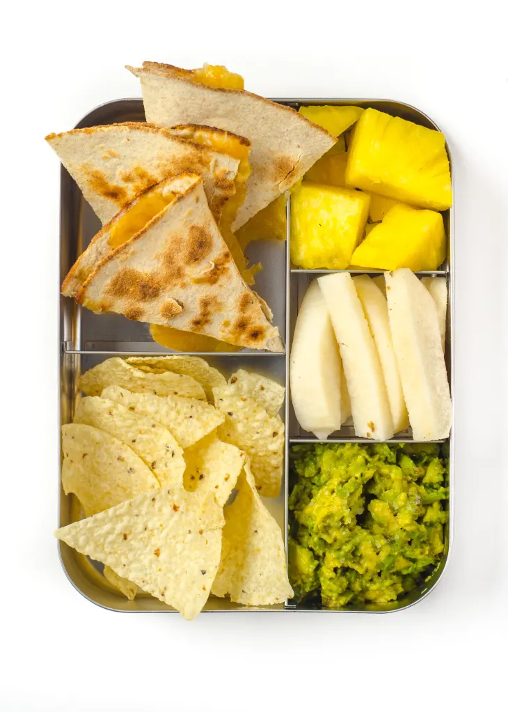 quesadillas in lunch box container with guacamole and fruit
