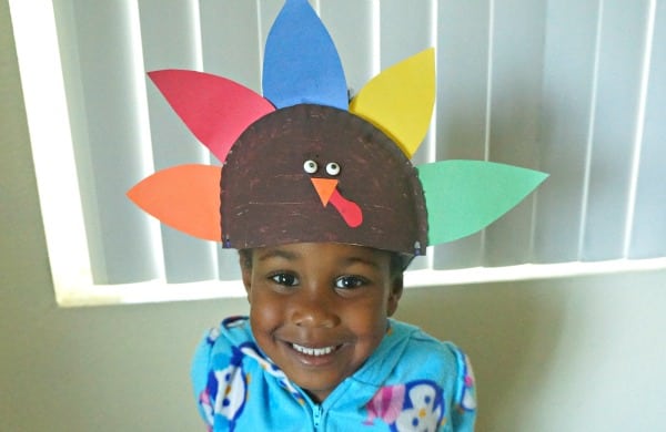 girl wearing her paper plate thanksgiving turkey hat craft