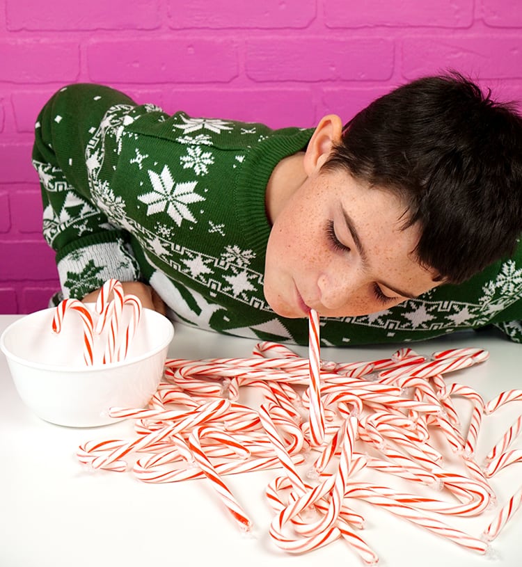 child playing minute to win it candy cane hook game