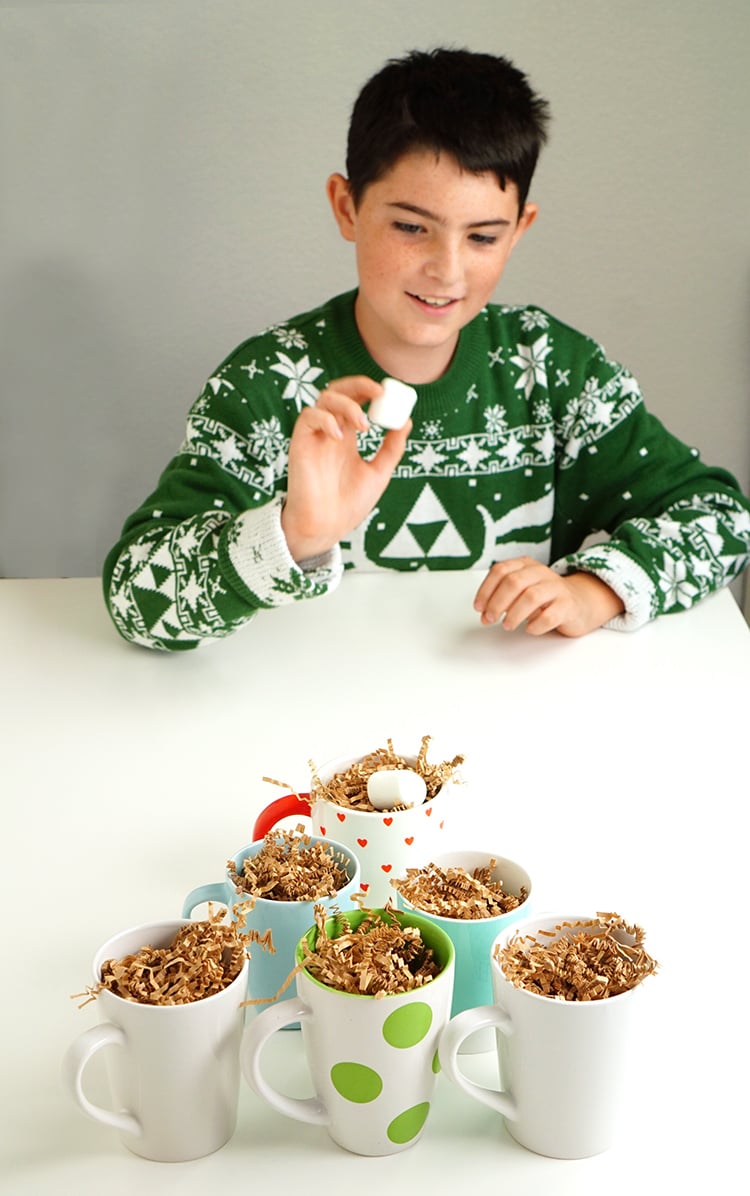 kid playing minute to win it christmas party games hot chocolate marshmallow toss game