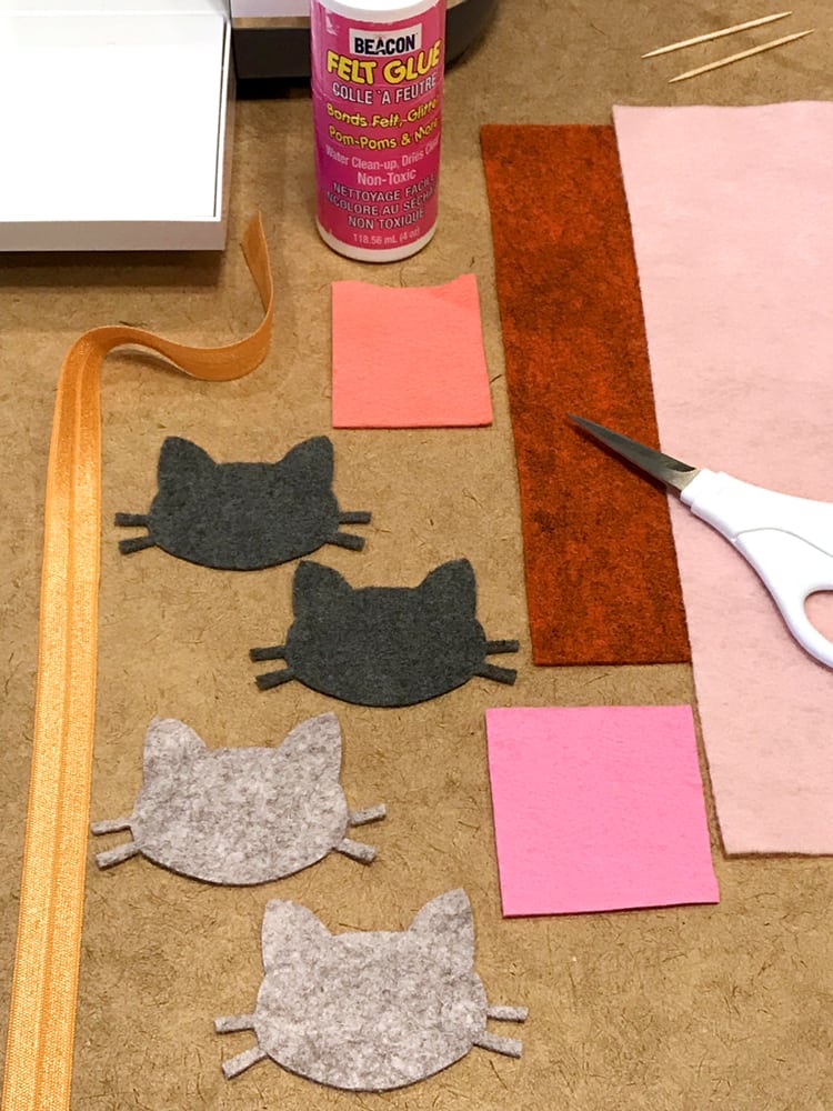 cut out felt cat heads and more scrap pieces with craft supplies