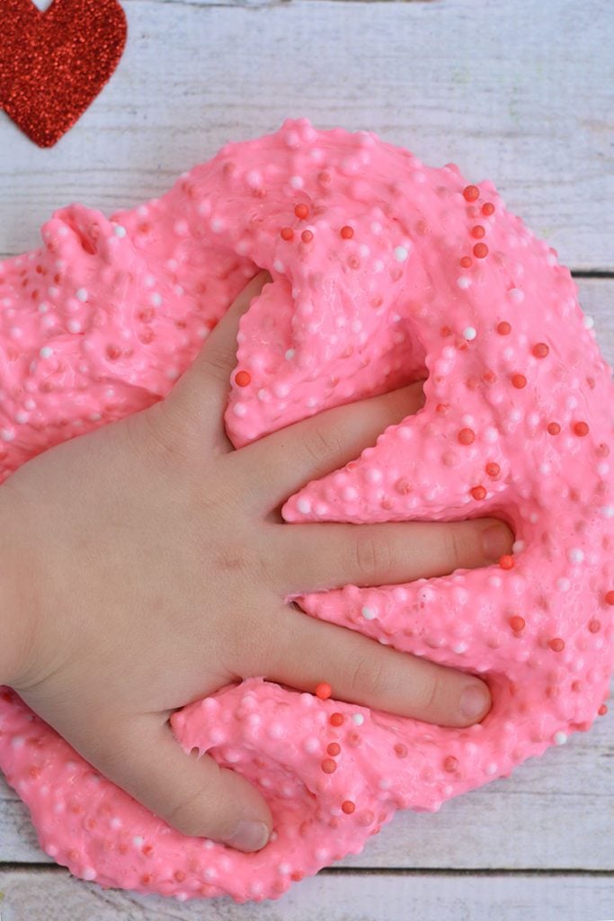 small hand squishing valentines day pink foam slime 