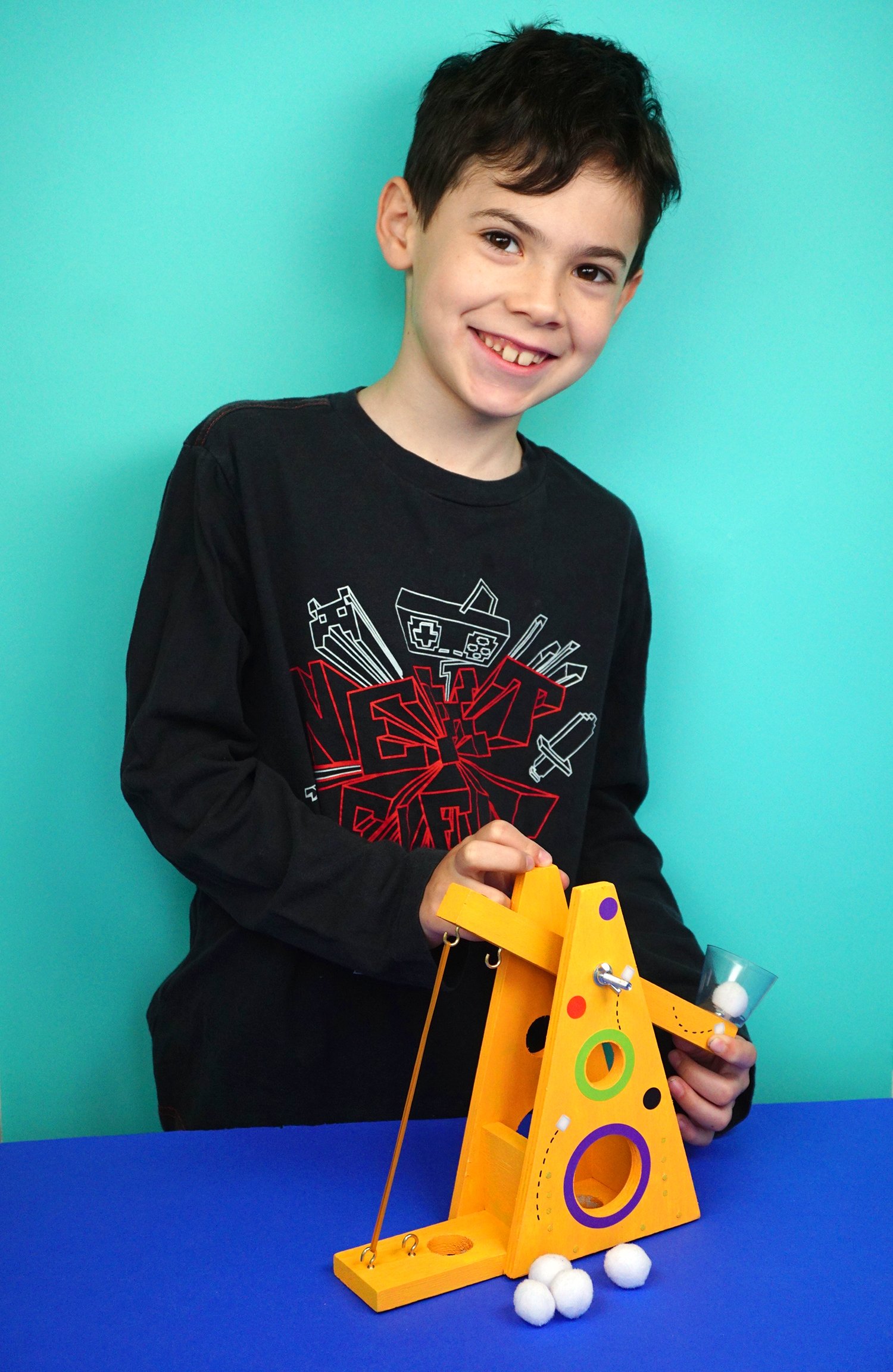 cute smiling boy playing with woodworkers club marshmallow launcher