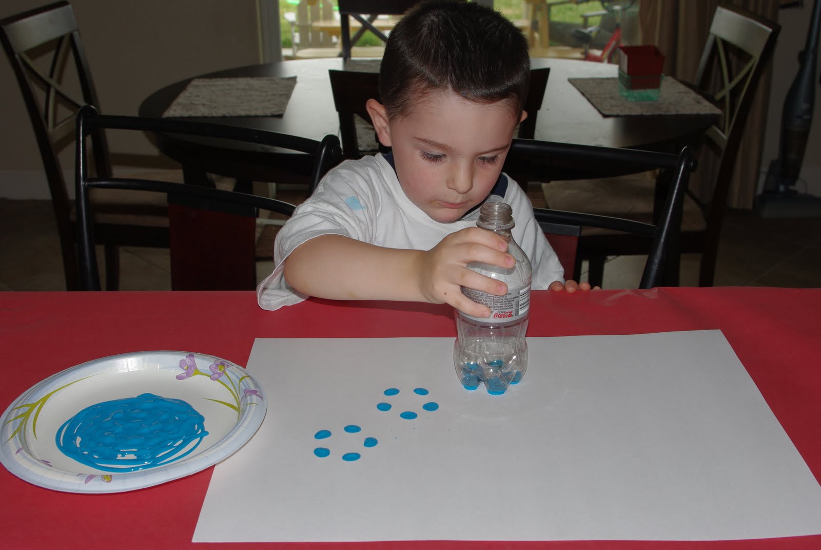 kid stamping flowers with bottom of bottle onto paper
