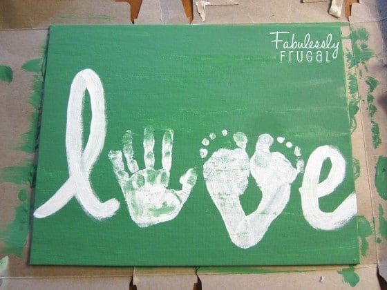 \"LOVE\" painted on canvas using child\'s handprint for the \'O\' and two feet prints to make the \"V\"