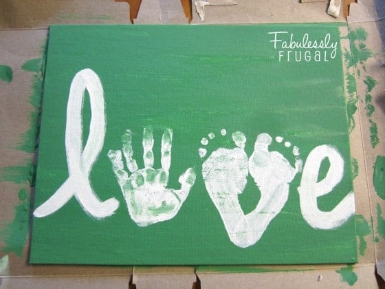 "LOVE" painted on canvas using child's handprint for the 'O' and two feet prints to make the "V"