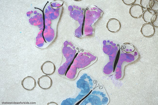 a group of cut out keychains of children's feet prints made to look like butterflies