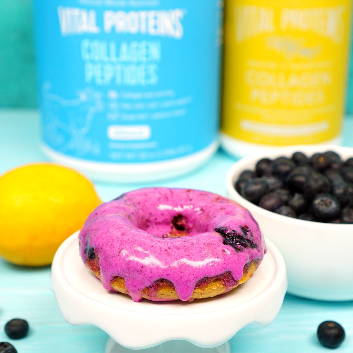 glazed donut on dish and dish of blueberries lemon and proteins in background