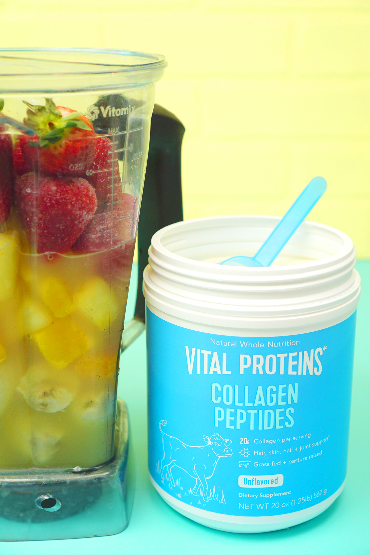 Jar of Vital Proteins Collagen Peptides next to a blender of fruit for a tropical smoothie