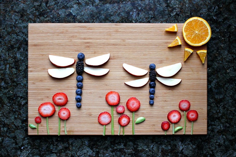 dragonflies, sun and flowers all made from fruits