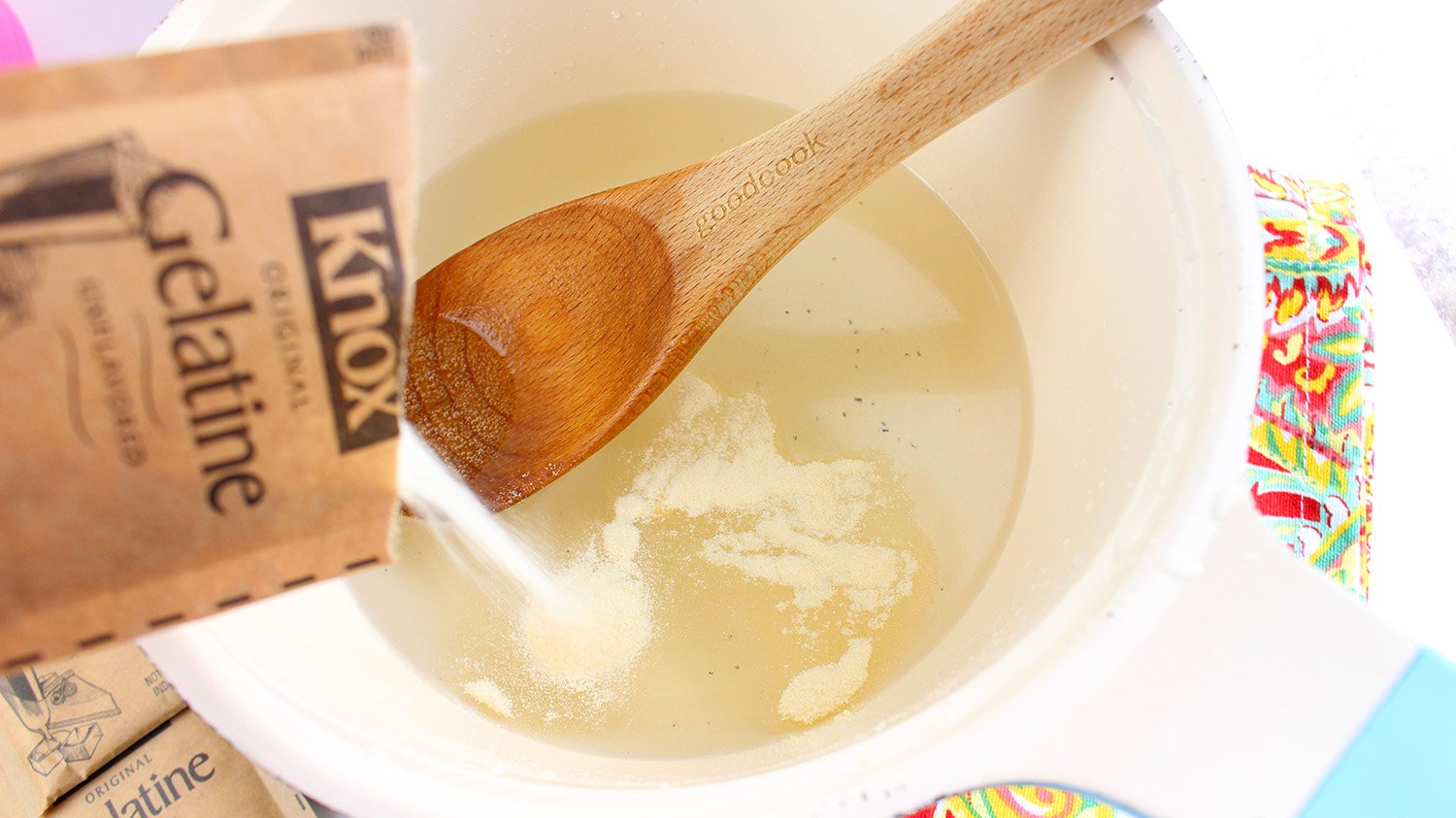 mixing ingredients for jello shots in mixing bowl with wooden spoon