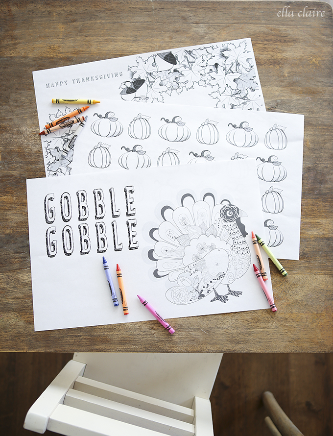 Several styles of Thanksgiving coloring placemats on wood background with crayons