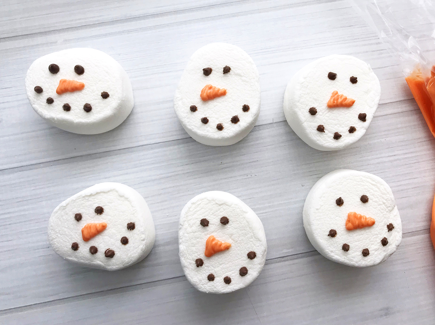 adding carrot noses to marshmallow snow men