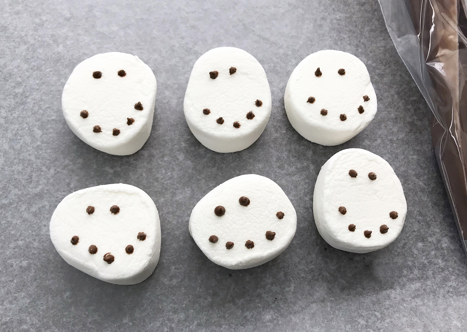 decorating marshmallows with snowman faces