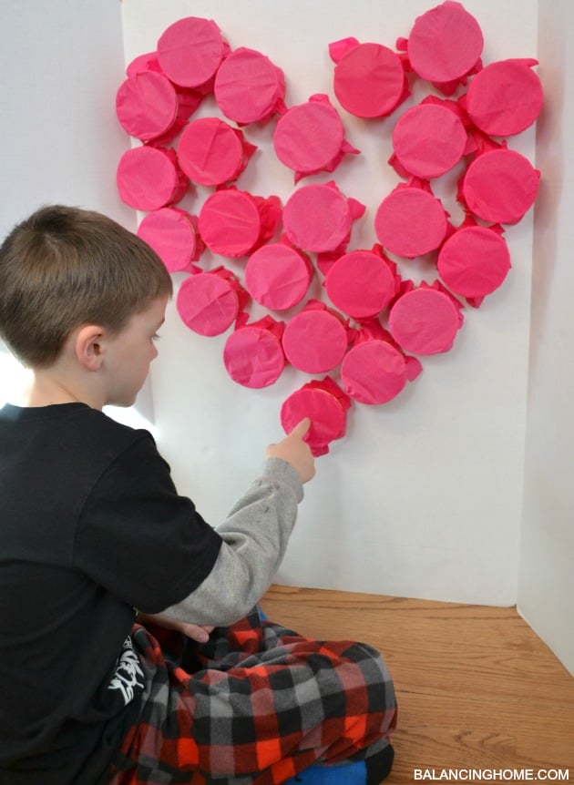 kid popping valentine hearts in classroom