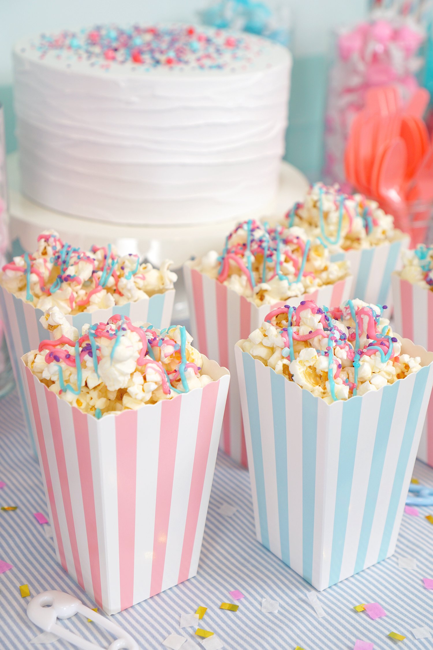 Pink and blue striped popcorn boxes filled with pink and blue drizzled popcorn