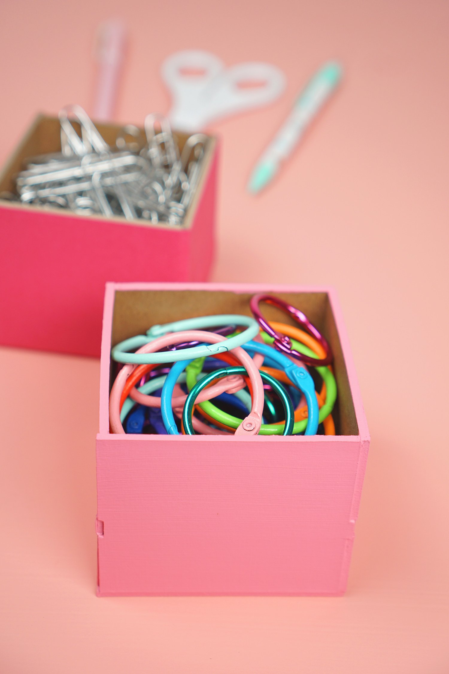 Pink desk organizer box filled with colorful binder rings and office supplies