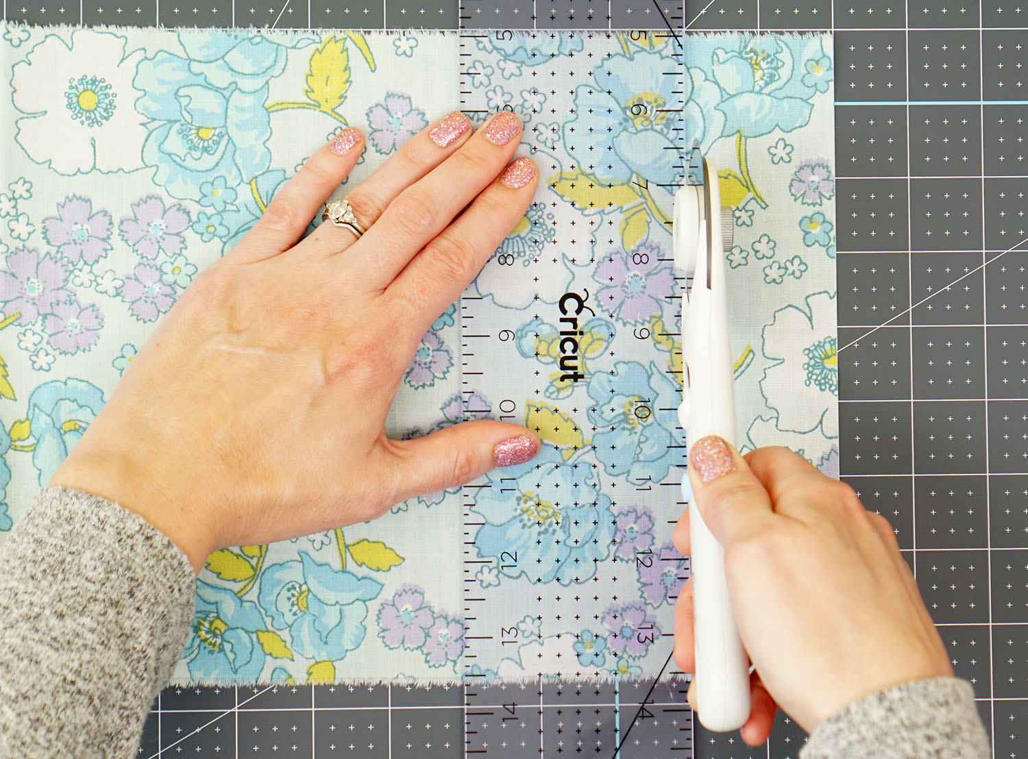hands using cricut rotary cutting tool to cut materials