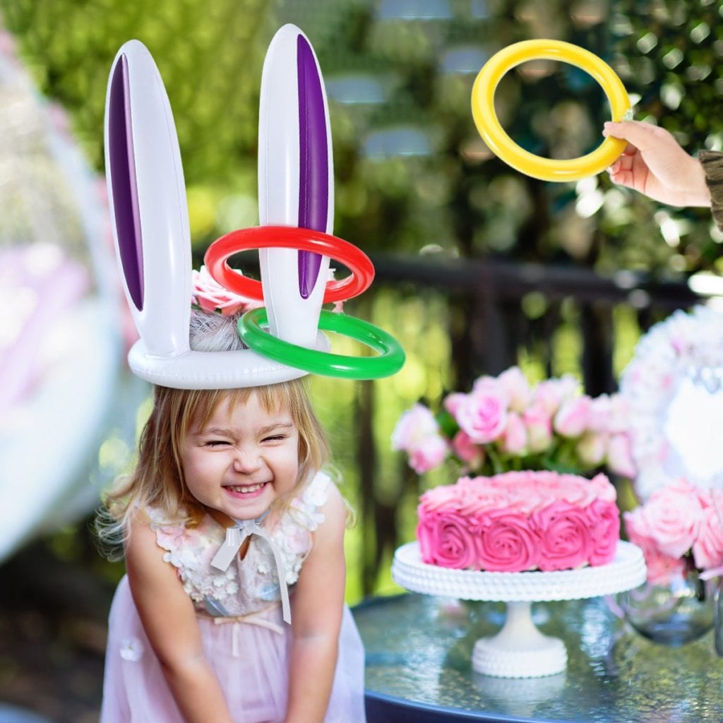 little girl with rabbit balloon hat getting rings tossed on her ears