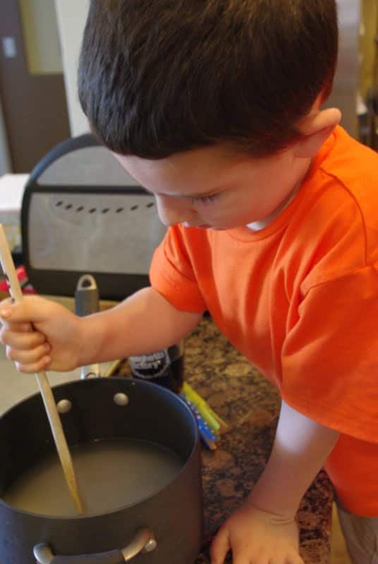 kid mixing sugar water for rock candy science experiment